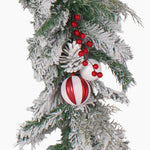 A festive Christmas garland branch decoration featuring a white pinecone, red and white ornaments with and clusters of red berries, isolated on a white background.