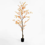 Artificial tree with orange leaves in a pot on a white background
