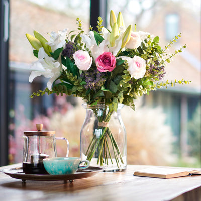 Bouquet of flowers on a table with a teacup and tea set in the background.