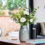 Vase with flowers on a wooden table in a living room