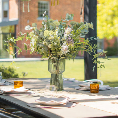 Outdoor table setting with floral centerpiece and hanging lanterns