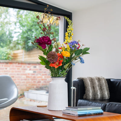 Living room with a black sofa, wooden coffee table, and colorful flowers in a vase.