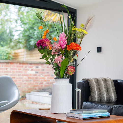 Colorful flowers in a vase on a wooden table in a living room.