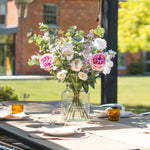 Outdoor table setting with flowers and glasses on a patio