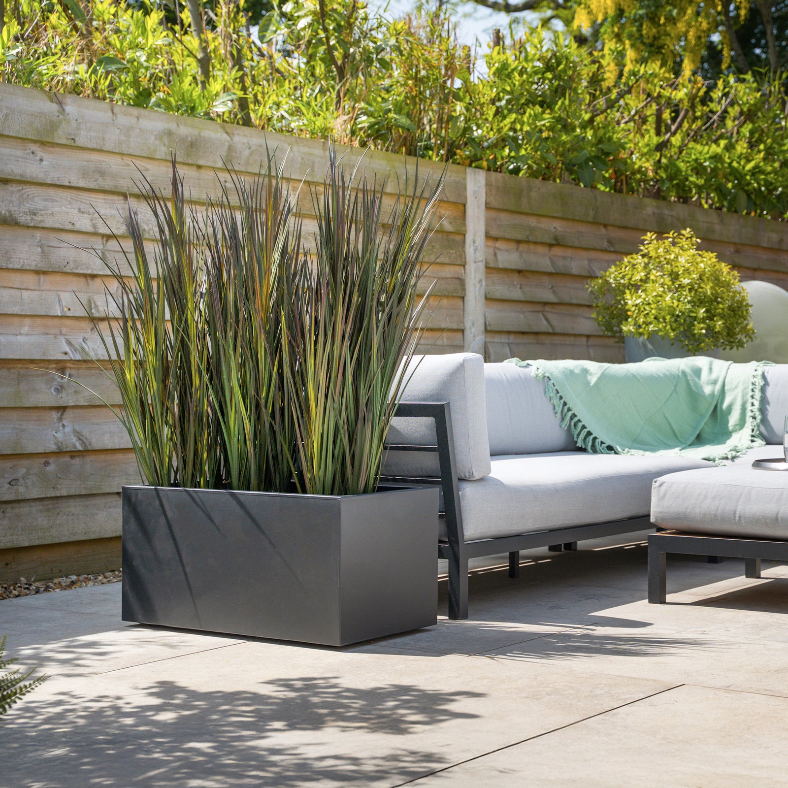 Outdoor patio with a sofa, planters, and wooden fence