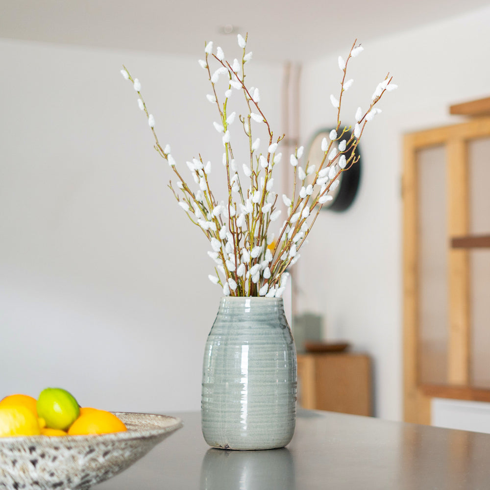 Decorative vase with willow branches on a table in a home setting