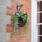 Hanging basket with pink flowers against a brick wall
