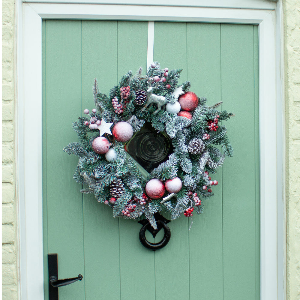 Decorative Christmas wreath with ornaments on a green door