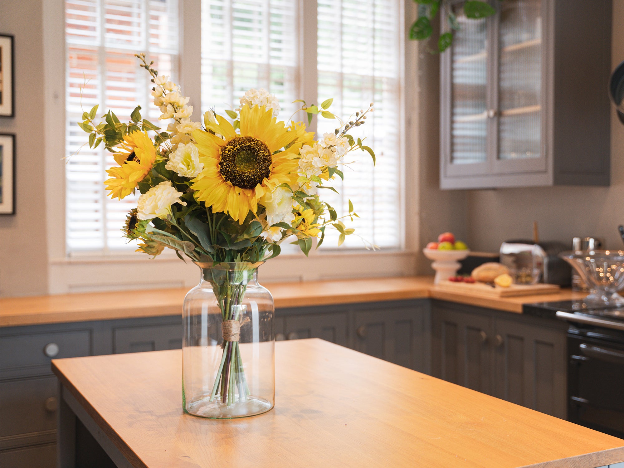 Bright yellow bouquet in a clear vase on a kitchen counter.