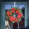 Christmas wreath with red flowers and pine cones on a glass door