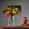 Bouquet of flowers in a clear vase on a wooden table with a blurred background