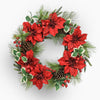 Christmas wreath with red flowers, greenery, and pinecones on a white background