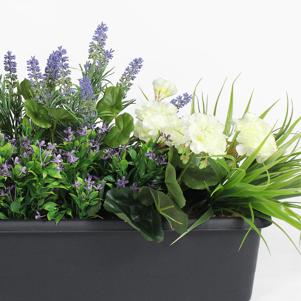 Artificial plants including lavender and white flowers in a black pot on a white background