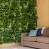 Living wall with greenery next to a brown sofa in a room with a glass door.