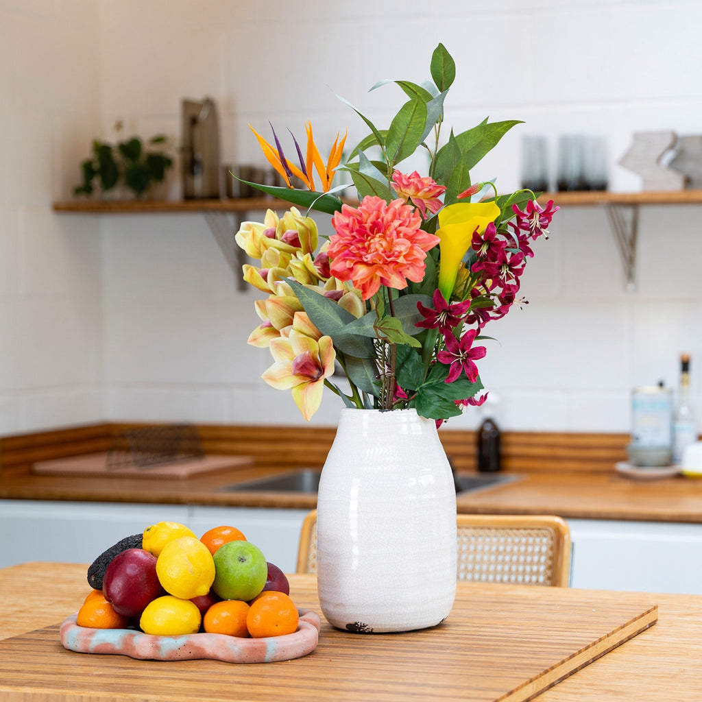 Kitchen counter with a vase of flowers and a fruit platter.