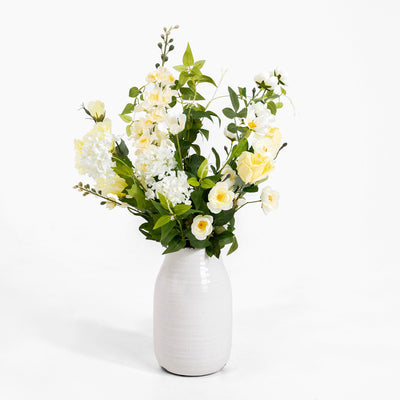 White vase with a bouquet of white and yellow flowers on a white background