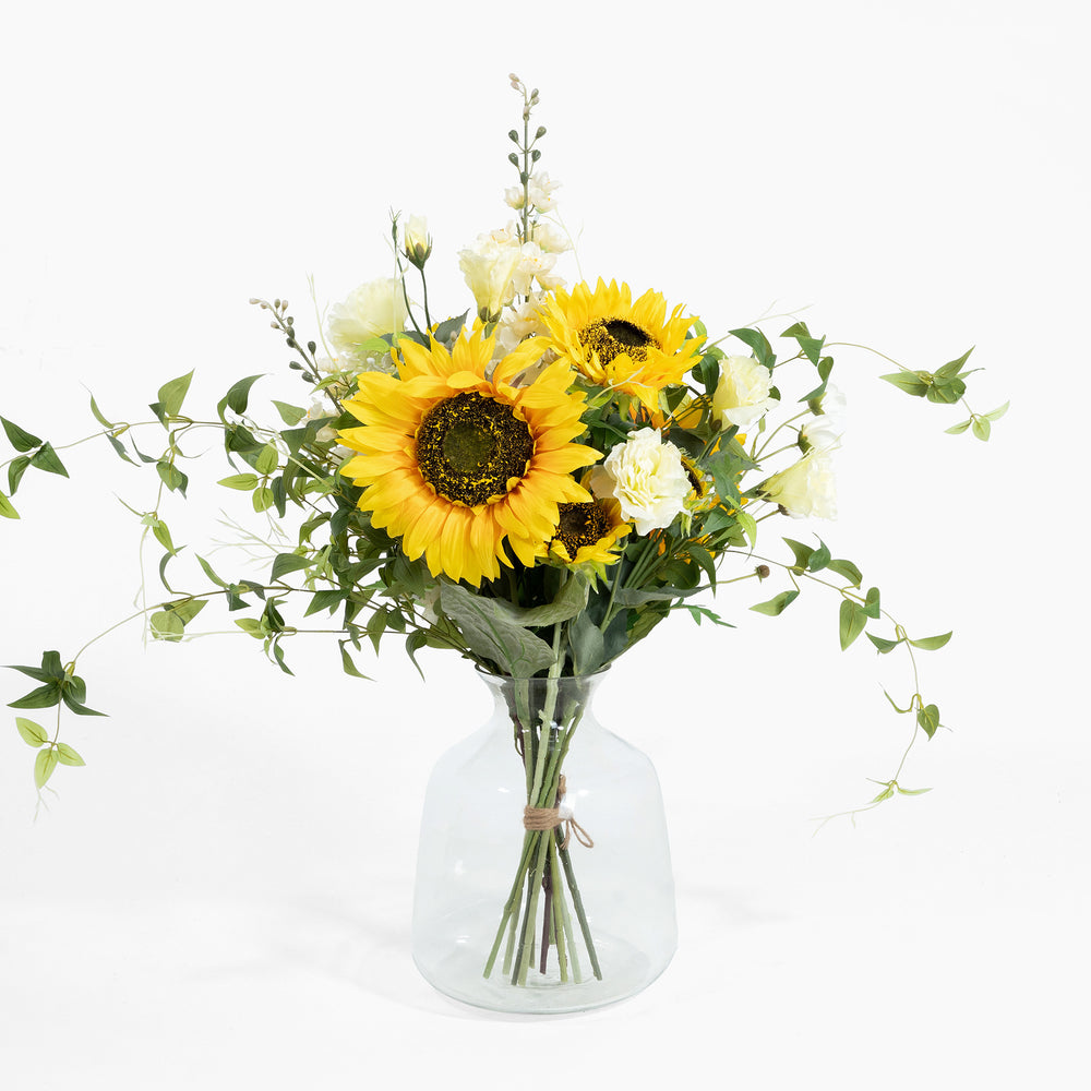 Bouquet of sunflowers and white flowers in a clear vase on a white background