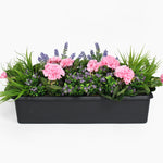 Floral arrangement in a black planter on a white background