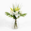 Bouquet of white and yellow flowers in a clear glass vase on a white background