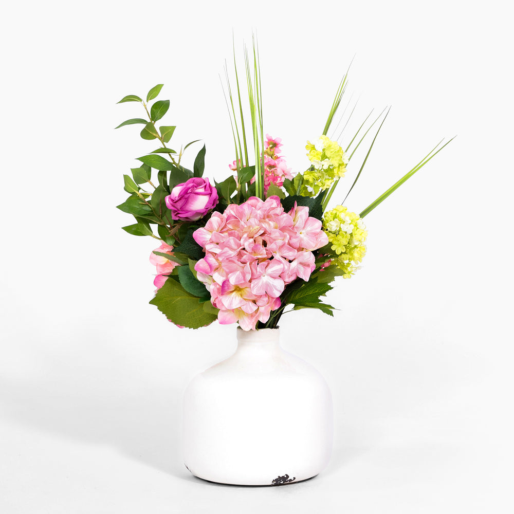 Floral arrangement with pink and yellow flowers in a white vase on a white background
