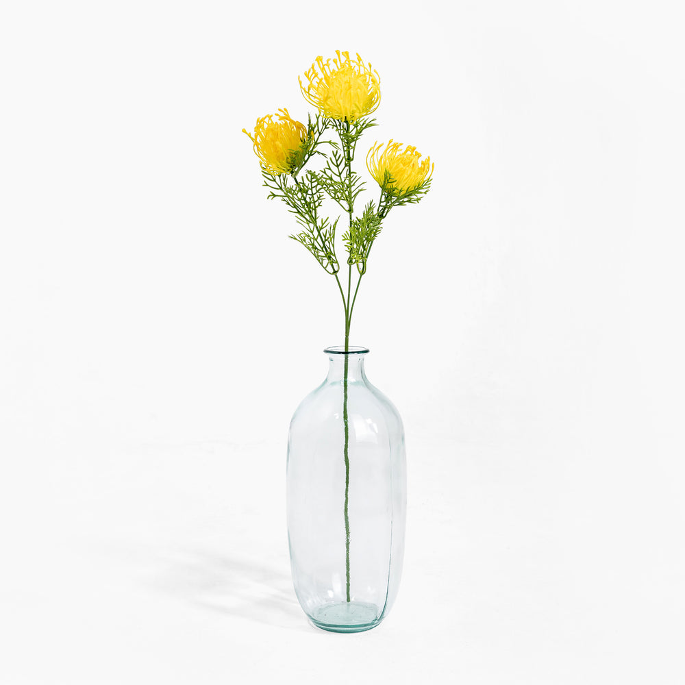 Clear glass vase with yellow flowers on a white background
