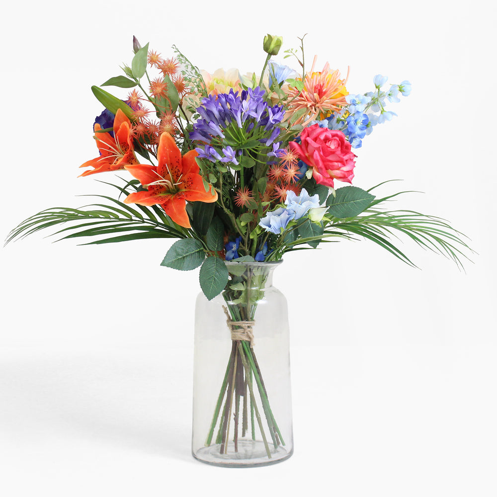 Bouquet of colorful flowers in a clear vase on a white background