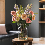 Bouquet of flowers in a vase on a wooden table in a living room.