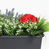 Container with artificial plants and flowers including red flowers, green leaves, and white flowers on a white background.