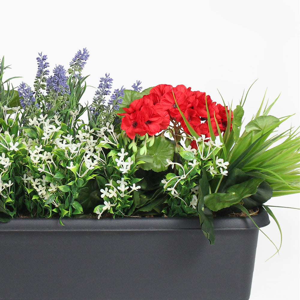 Container with artificial plants and flowers including red flowers, green leaves, and white flowers on a white background.