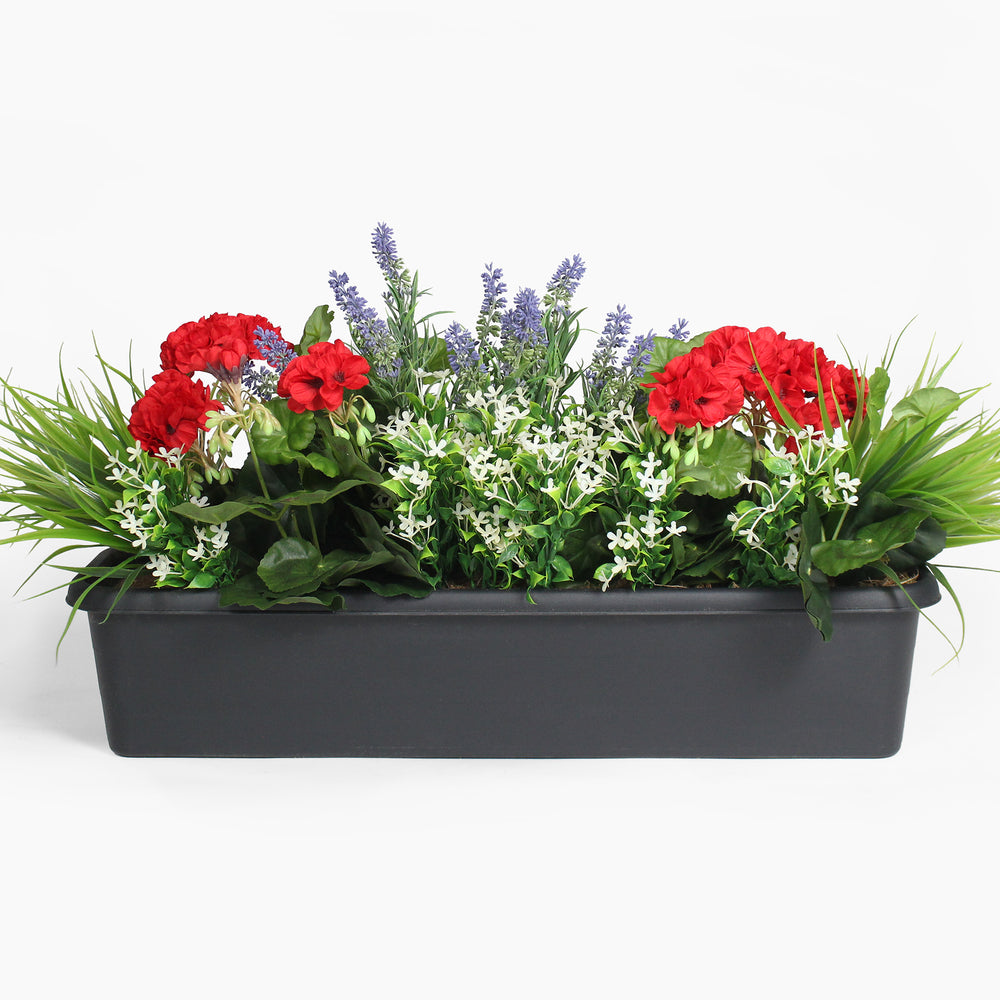 Black rectangular planter with red flowers, green grass, and purple lavender on a white background