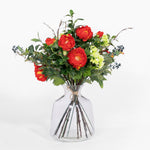 Bouquet of red and green flowers in a clear vase on a white background