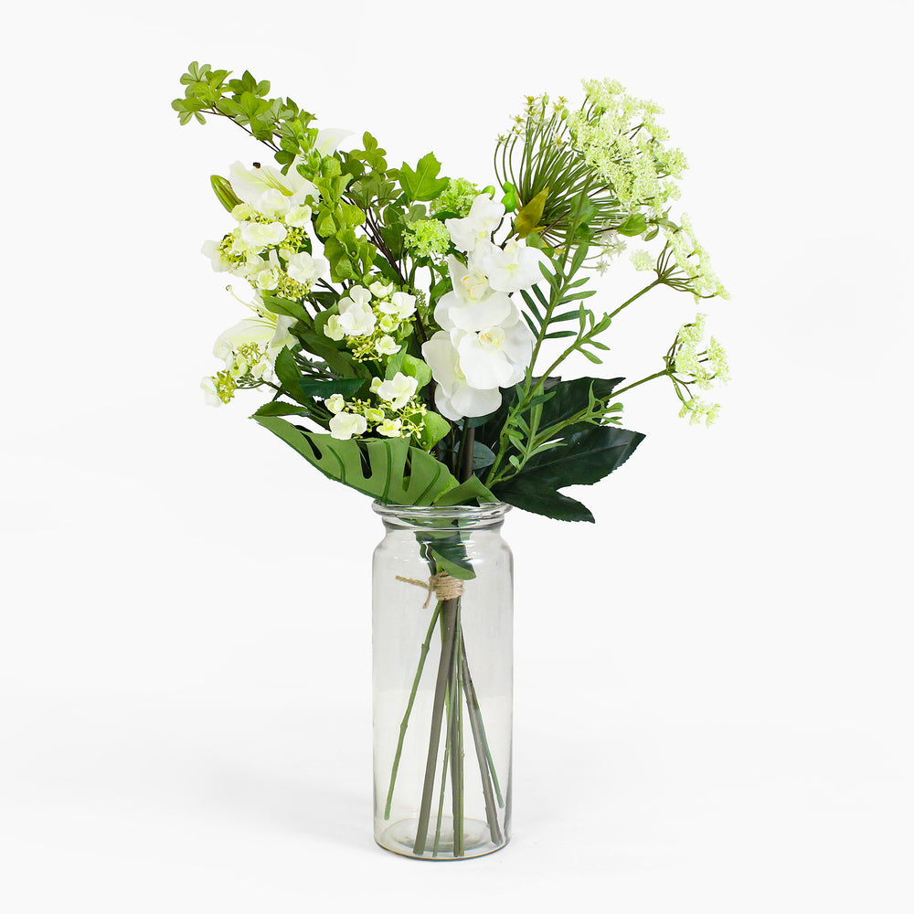 Bouquet of green and white flowers in a clear glass vase on a white background