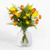 Bouquet of yellow and orange flowers in a clear glass vase on a white background