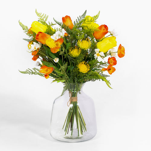 Bouquet of yellow and orange flowers in a clear glass vase on a white background
