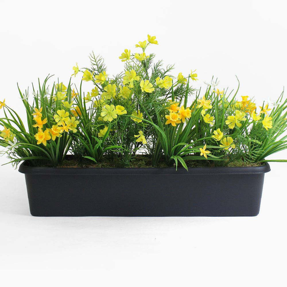Artificial greenery with yellow flowers in a black planter on a white background