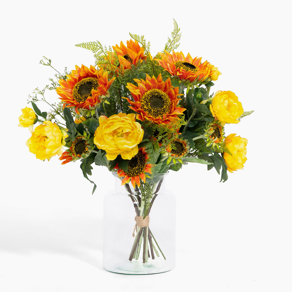 Bouquet of sunflowers and yellow flowers in a clear vase on a white background