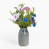 Gray ceramic vase with a bouquet of colorful flowers on a white background