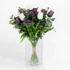 Bouquet of purple and white tulips in a clear glass vase on a white background