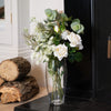 Vase with flowers on a fireplace hearth next to stacked logs
