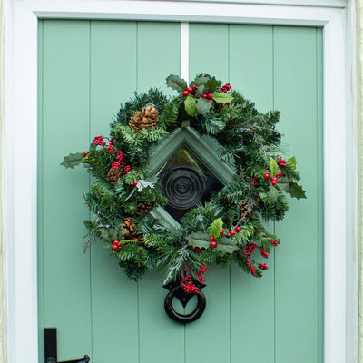 Artificial winter berry wreath on green front door