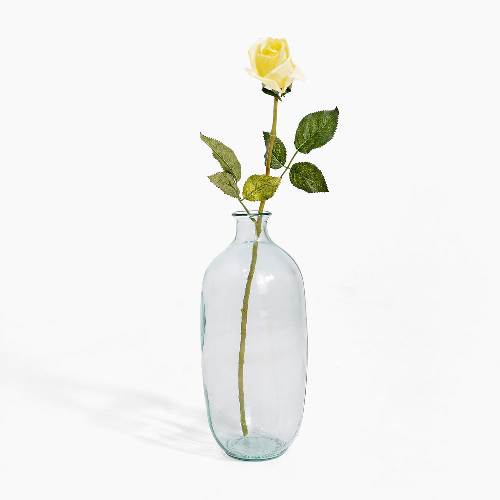 Clear glass bottle with a single yellow rose on a white background