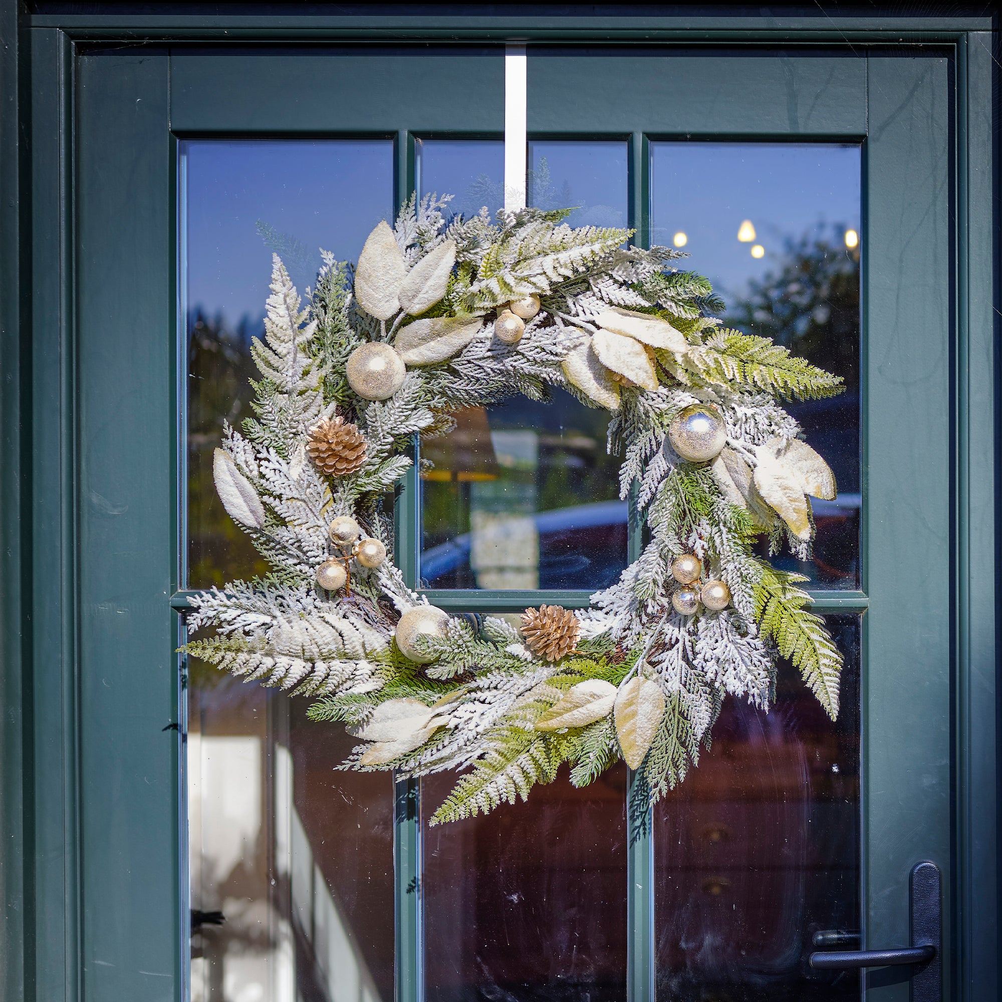 Decorative wreath with greenery and ornaments hanging on a door.