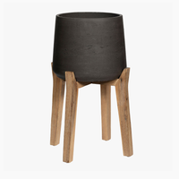 Black planter with wooden legs on a white background