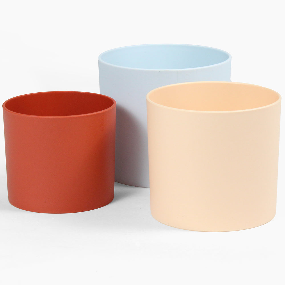 Three colorful plant pots in red, blue, and beige on a white background