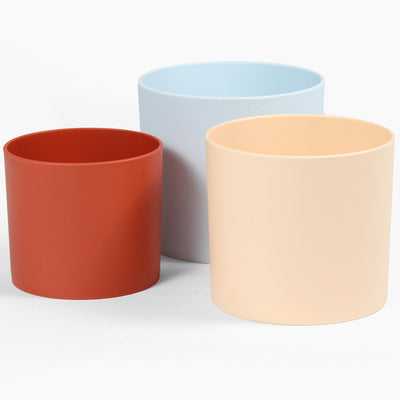 Three colorful plant pots in red, blue, and beige on a white background