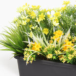 Close up of artificial planter with yellow flowers in a black pot on a white background
