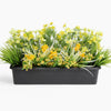 Artificial greenery with yellow flowers in a black container on a white background