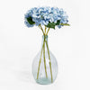 Clear glass vase with blue hydrangeas on a white background
