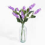 Clear glass vase with purple flowers on a white background