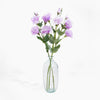 Clear glass vase with purple flowers on a white background